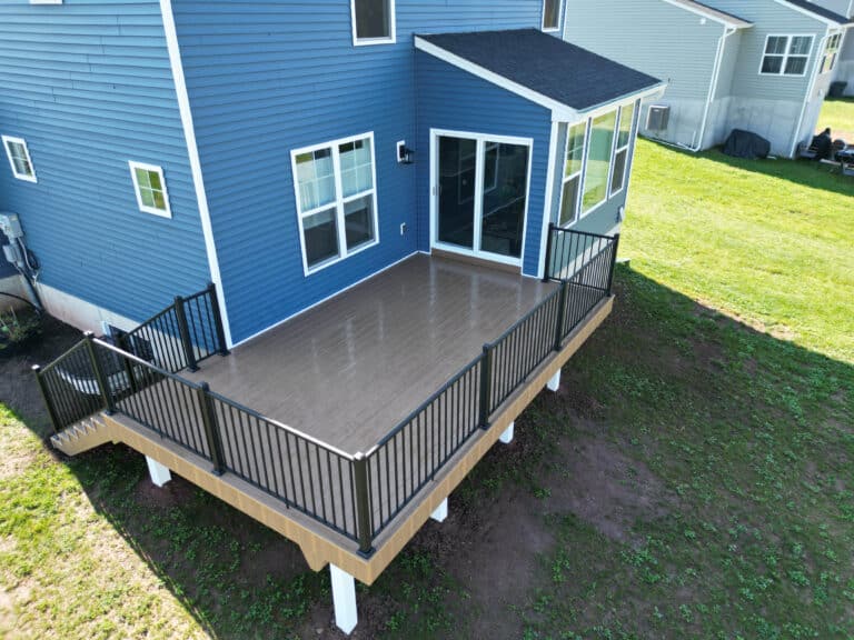 A 10x10 deck behind a blue house with black railing and a staircase leading down