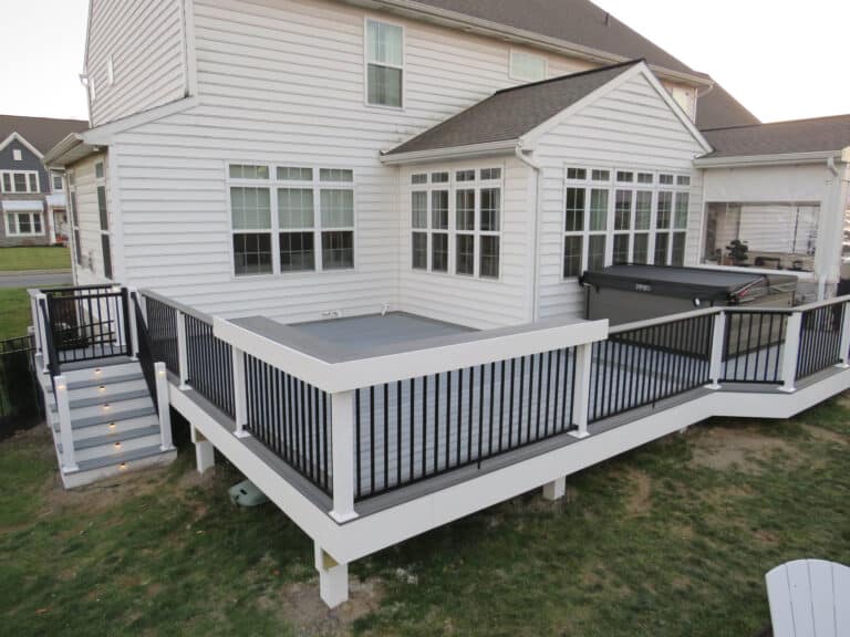 A 12x20 deck in the back of a house with a closed hot tub on it and stairs leading down to the backyard