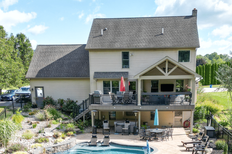 vinyl deck behing tan house with gray shingle roof done by vinyl deck contractor in PA overlooking pool