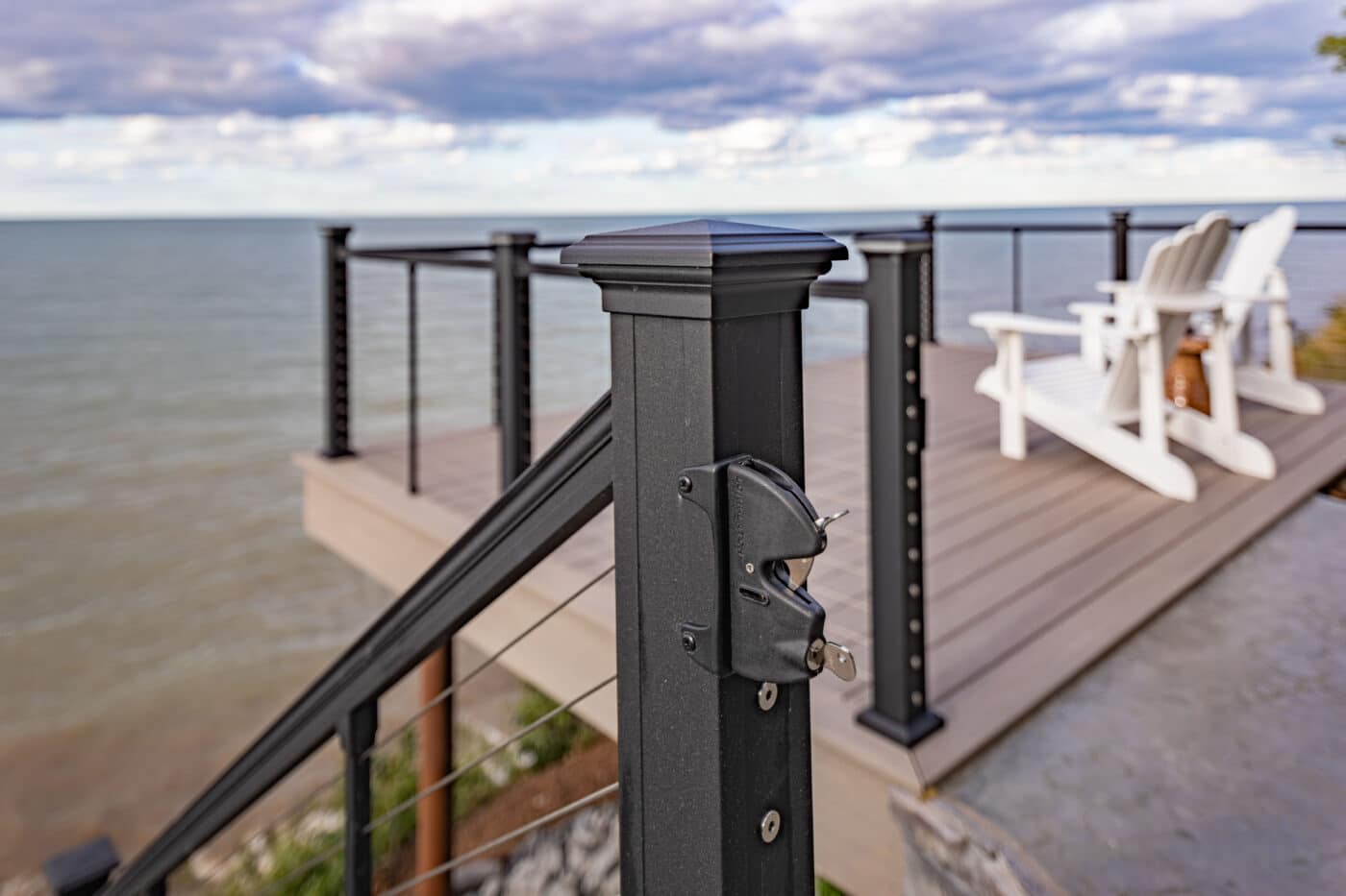 deck with black railing and two white aidrondack chiars overlooking the ocean