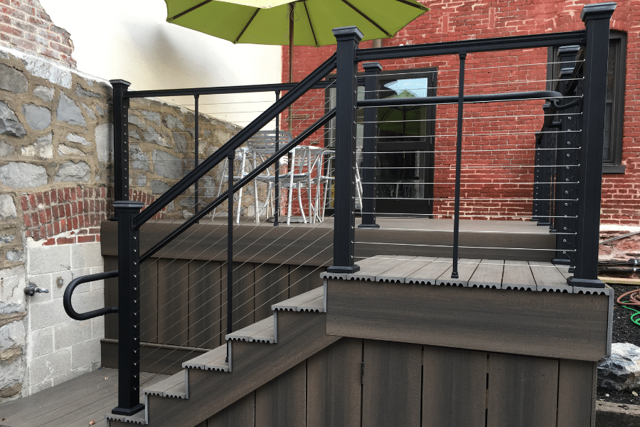 vinyl deck attached to back of brick building with white table with green umbrella over it